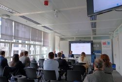 dr Edytą Figurą-Góralczyk z Uniwersytetu Ekonomicznego w Krakowie prezentująca wykład podczas Międzynarodowej Konferencji Naukowej „Naruszenia prywatności i dóbr osobistych w konflikcie praw” („Privacy and Personality Rights Violations in the Conflict of Laws”). Na pierwszym planie słuchacze zebrani w sali wykładowej. W tle trójka naukowców, Pani doktor i dwóch mężczyzn. Za nimi ekran z wyświetloną prezentacją.