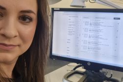 Dr Magdalena Maksymiuk, w bibliotece w trakcie stażu na Uniwersytecie Wileńskim. Na pierwszym planie Pani dr., w tle komputer z uruchomioną kwerendą biblioteczną.