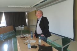 Prof. Zbigniew Lewicki stojący za stołem na katedrze w sali wykładowej prowadzi spotkanie ze studentami.
